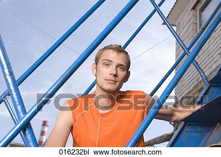 portrait of young man sitting on stairs listening to music on mp3 player View Large Photo Image Stock Image - portrait of young man sitting on stairs listening to music on mp3 player. Fotosearch