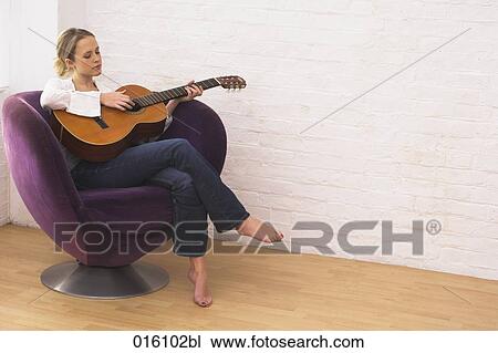 portrait of young woman sitting at home playing guitar View Large Photo Image Stock Image - portrait of young woman sitting at home playing guitar. Fotosearch
