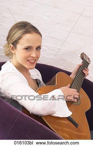 portrait of young woman sitting at home playing guitar View Large Photo Image Stock Image - portrait of young woman sitting at home playing guitar. Fotosearch