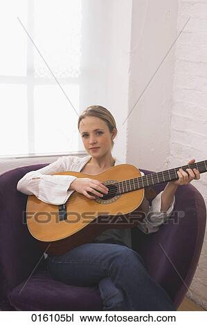 portrait of young woman sitting at home playing guitar View Large Photo Image Stock Image - portrait of young woman sitting at home playing guitar. Fotosearch