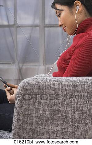 side view of young japanese woman sitting in arm chair listening to music on ipod View Large Photo Image Stock Image - side view of young japanese woman sitting in arm chair listening to music on ipod. Fotosearch