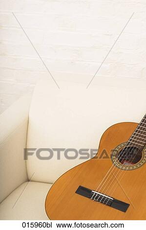 still lif of guitar on white arm chair View Large Photo Image Stock Image - still lif of guitar on white arm chair. Fotosearch