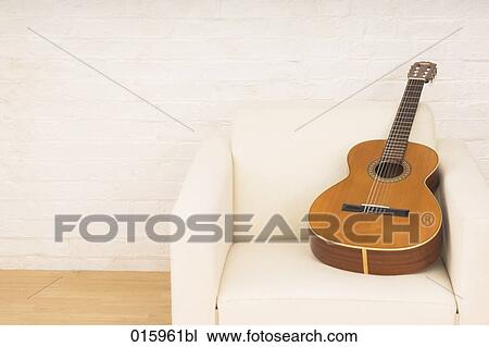 still lif of guitar on white arm chair View Large Photo Image Stock Image - still lif of guitar on white arm chair. Fotosearch