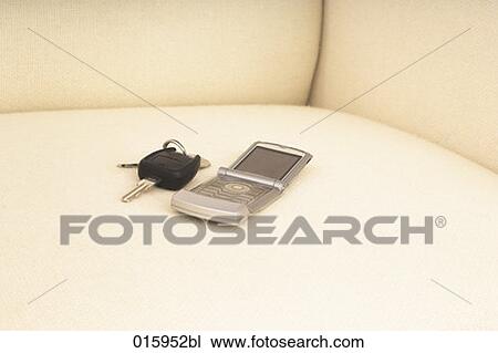 Stock Image - still life of car key and mobile phone on white arm chair. Fotosearch