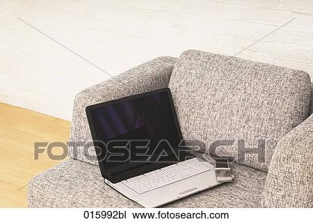 still life of open laptop computer and mobile phone on grey arm chair View Large Photo Image Stock Image - still life of open laptop computer and mobile phone on grey arm chair. Fotosearch