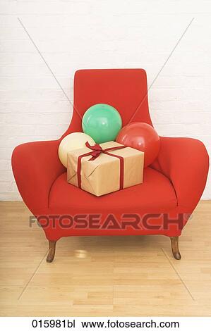 still life of three colourful balloons and present on red arm chair View Large Photo Image Stock Image - still life of three colourful balloons and present on red arm chair. Fotosearch