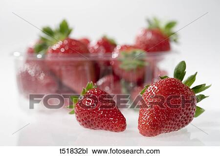 Strawberries in foreground and in plastic container, close-up View Large Photo Image Stock Image - Strawberries in foreground and in plastic container, close-up . Fotosearch