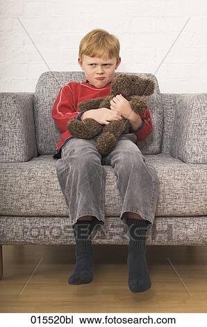 sulking young boy sitting in arm chair holding teddy bear View Large Photo Image Stock Image - sulking young boy sitting in arm chair holding teddy bear. Fotosearch