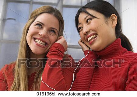 two young woman listening to music sharing earphones View Large Photo Image Stock Image - two young woman listening to music sharing earphones. Fotosearch