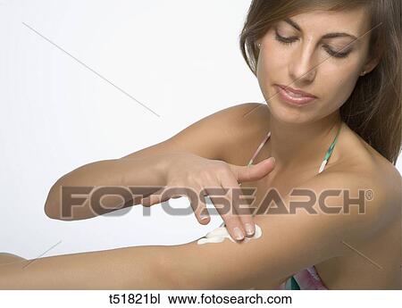 Stock Image - Woman applying moisturizer to shoulder . Fotosearch