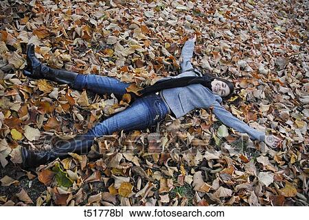 Woman lying in autumn leaves View Large Photo Image Stock Image - Woman lying in autumn leaves . Fotosearch