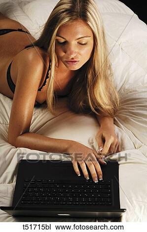Woman lying on bed using laptop View Large Photo Image Stock Image - Woman lying on bed using laptop . Fotosearch