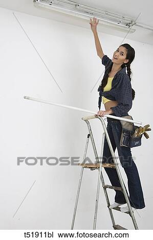 Stock Image - Woman Standing On Ladder . Fotosearch