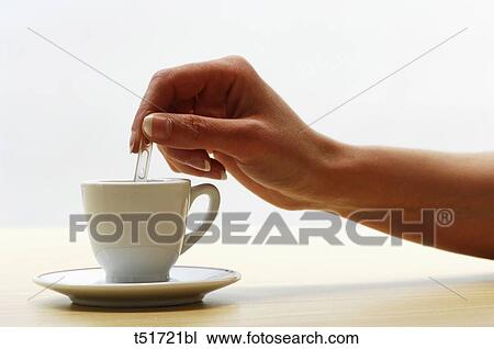 Stock Image - Woman's hand stirring coffee cup . Fotosearch