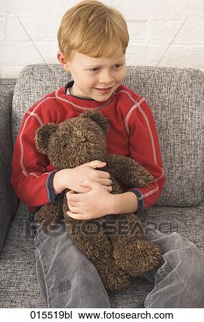 young boy sitting in arm chair cuddling teddy bear View Large Photo Image Stock Image - young boy sitting in arm chair cuddling teddy bear. Fotosearch