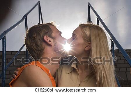 Stock Image - young couple kissing at sunset. Fotosearch