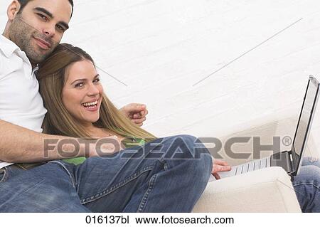 young couple sitting together working with laptop computer View Large Photo Image Stock Image - young couple sitting together working with laptop computer. Fotosearch