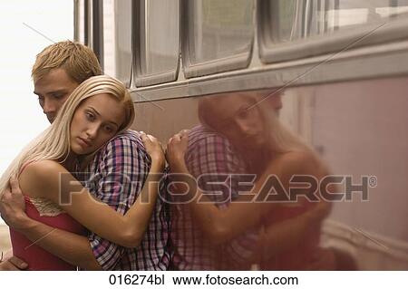 Stock Image - young couple standing at bus embracing woman looking sad. Fotosearch