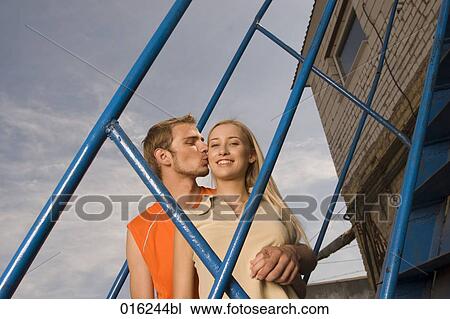 young couple standing on stairs man kissing woman on cheek View Large Photo Image Stock Image - young couple standing on stairs man kissing woman on cheek. Fotosearch