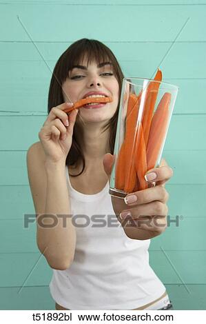 Stock Image - Young woman eats carrot . Fotosearch