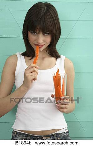 Stock Image - Young woman eats carrot . Fotosearch