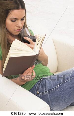 young woman sitting in arm chair reading book and drinking glass of red wine View Large Photo Image Stock Image - young woman sitting in arm chair reading book and drinking glass of red wine. Fotosearch