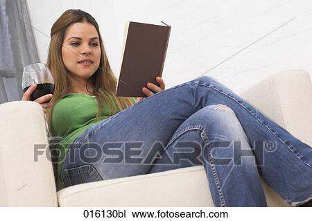 young woman sitting in arm chair reading book and drinking glass of red wine View Large Photo Image Stock Image - young woman sitting in arm chair reading book and drinking glass of red wine. Fotosearch