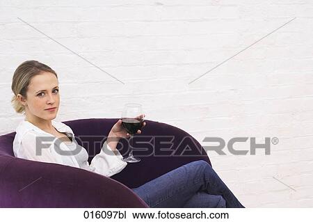 young woman sitting in purple arm chair holding glass of red wine View Large Photo Image Stock Image - young woman sitting in purple arm chair holding glass of red wine. Fotosearch