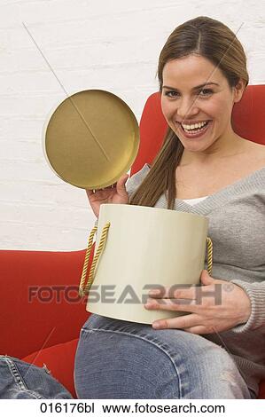 young woman sitting in red arm chair opening present View Large Photo Image Stock Image - young woman sitting in red arm chair opening present. Fotosearch