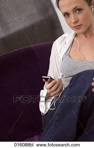 young woman sitting on arm chair listening to music on mp3 player View Large Photo Image Stock Image - young woman sitting on arm chair listening to music on mp3 player. Fotosearch