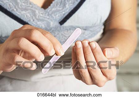 Stock Image - close-up of young woman manicuring her fingernails. Fotosearch