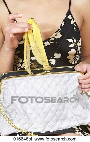 close-up of young woman putting banana peel into ther handbag View Large Photo Image Stock Image - close-up of young woman putting banana peel into ther handbag. Fotosearch