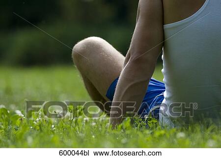 detail of young man sitting on lawn in park View Large Photo Image Stock Image - detail of young man sitting on lawn in park. Fotosearch