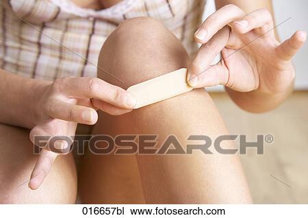 detail of young woman putting band-aid on her knee View Large Photo Image Stock Image - detail of young woman putting band-aid on her knee. Fotosearch