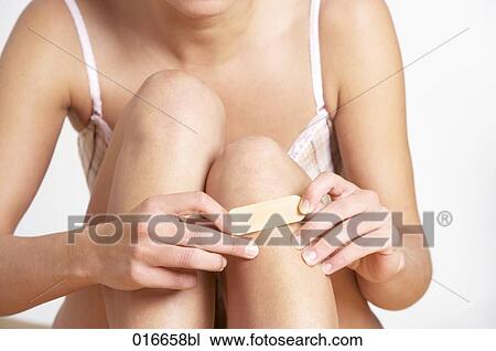 detail of young woman putting band-aid on her knee View Large Photo Image Stock Image - detail of young woman putting band-aid on her knee. Fotosearch