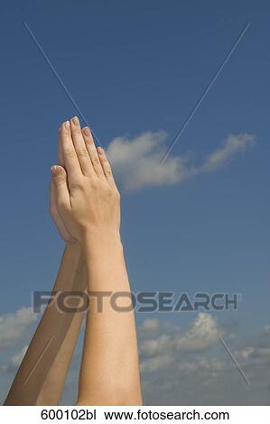 detail of young woman raising folded hands against sky View Large Photo Image Stock Image - detail of young woman raising folded hands against sky. Fotosearch