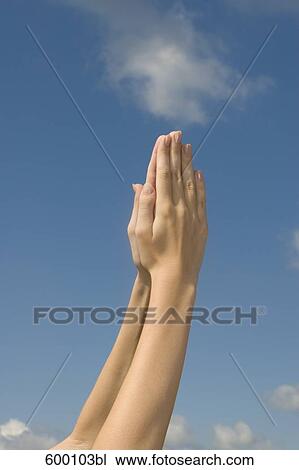 detail of young woman raising folded hands against sky View Large Photo Image Stock Image - detail of young woman raising folded hands against sky. Fotosearch