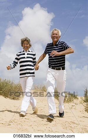 full body portrait of mature couple walking hand in hand on sandy beach View Large Photo Image Stock Image - full body portrait of mature couple walking hand in hand on sandy beach . Fotosearch