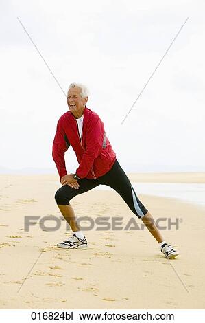 Stock Image - full body portrait of mature man exercising on beach. Fotosearch