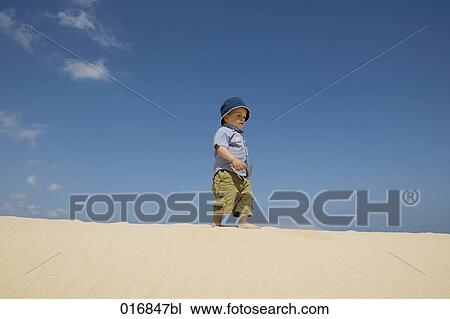 Stock Image - full body portrait of toddler walking on beach. Fotosearch