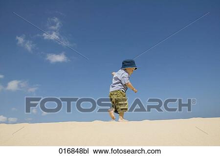 Stock Image - full body portrait of toddler walking on beach. Fotosearch