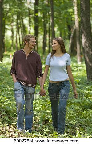 full body portrait of young couple walking hand in hand through forest View Large Photo Image Stock Image - full body portrait of young couple walking hand in hand through forest. Fotosearch
