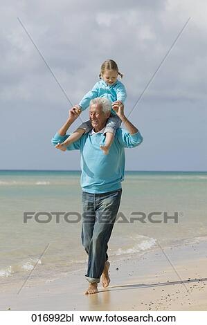 grandfather carrying young girl piggyback on beach View Large Photo Image Stock Image - grandfather carrying young girl piggyback on beach. Fotosearch