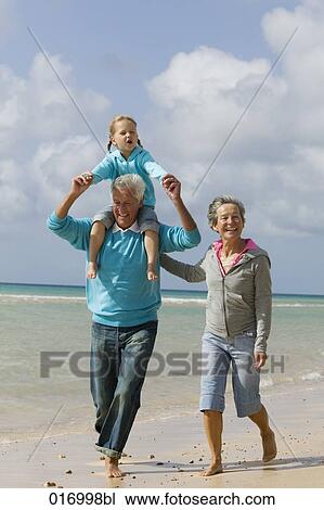 grandparents walking along beach with grandfather carrying young girl piggback View Large Photo Image Stock Image - grandparents walking along beach with grandfather carrying young girl piggback. Fotosearch