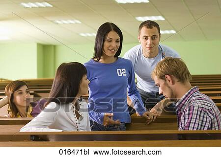 Stock Image - group of four young students talking during a break in lecture hall. Fotosearch