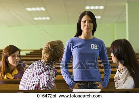 Stock Image - group of four young students talking during a break in lecture hall. Fotosearch
