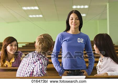 Stock Image - group of four young students talking during a break in lecture hall. Fotosearch