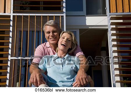 Stock Image - happy couple sitting in front of home. Fotosearch