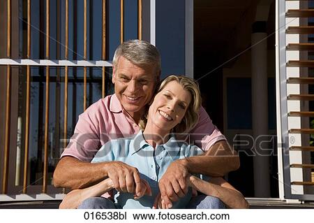 Stock Image - happy couple sitting in front of home. Fotosearch