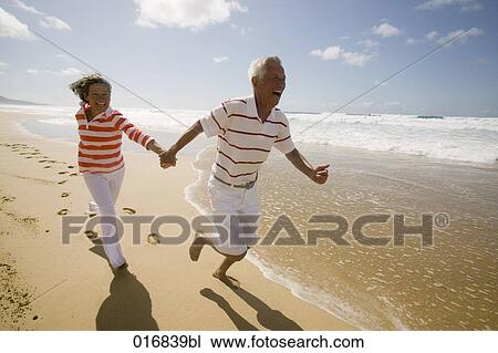 happy mature couple hand in hand running along beach View Large Photo Image Stock Image - happy mature couple hand in hand running along beach. Fotosearch